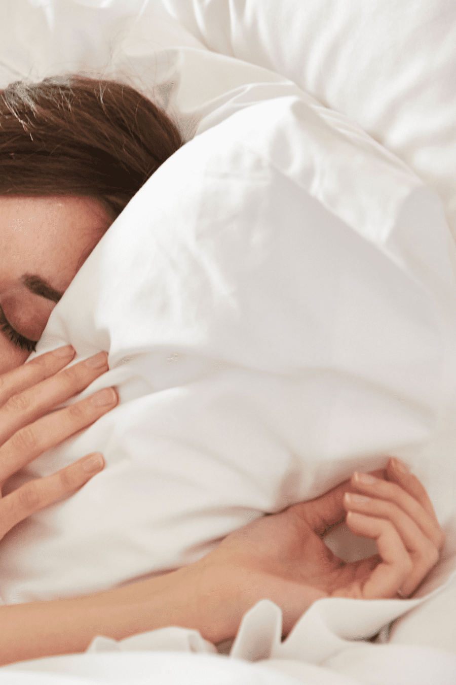 a woman relaxing on a pillow at her wellness retreat, eyes closed and wrapped in a cozy blanket