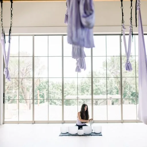 person using sound bowls in aerial yoga room